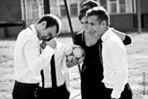 Веселый эпизод модельной фотосессии: мужчины модели и девушка с мячом в кадре смеются